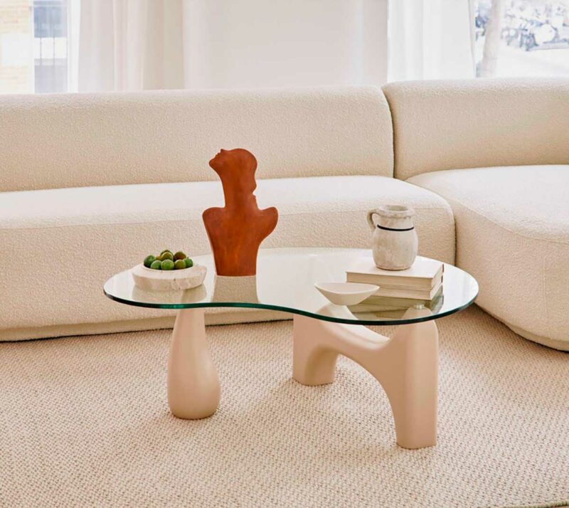 Table basse avec plateau haricot en verre sur une structure organique en bois beige