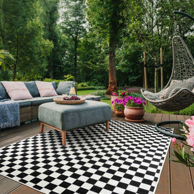 Terrasse avec tapis d'extérieur réversible à motifs damier noir et blanc